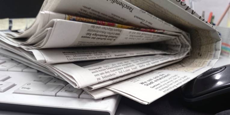 Zeitungen liegen auf einem Schreibtisch.