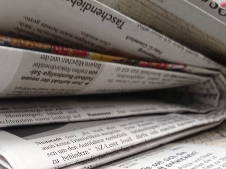 Zeitungen liegen auf einem Schreibtisch.