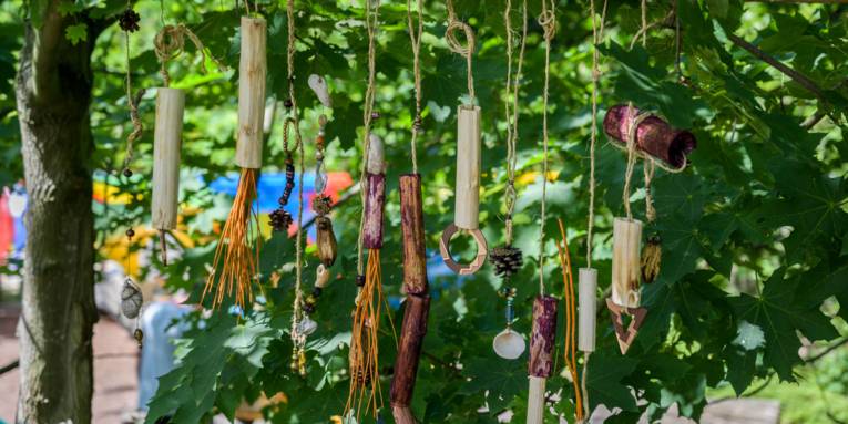 In einem Baum hängende Materialen, die eine Art Mobile ergeben und Töne erzeugen