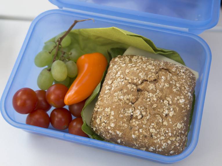 Brotdose mit Käsebrötchen, Tomaten und Weintrauben gefüllt 
