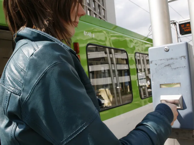 Frau entwertet Fahrkarte an blauem Stempelautomaten.