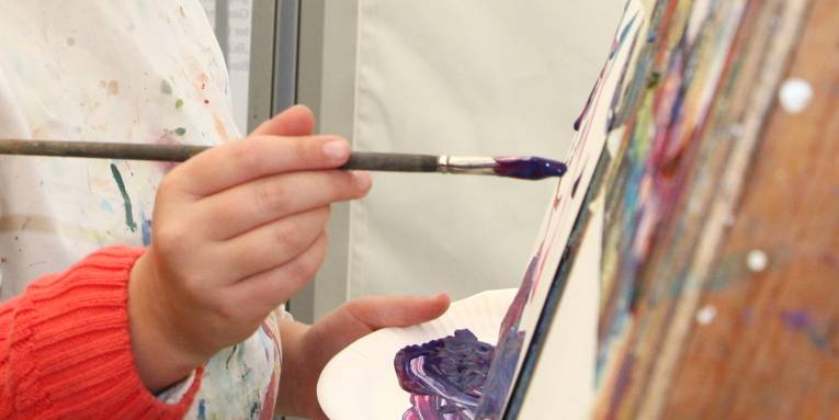 Mit einem Pinsel wird Farbe auf einen Malgrund aufgetragen.