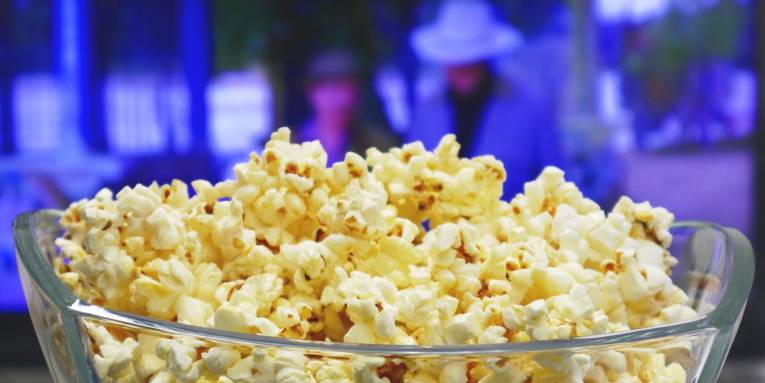 Popcorn in einer Schüssel, im Hintergrund läuft ein Film.
