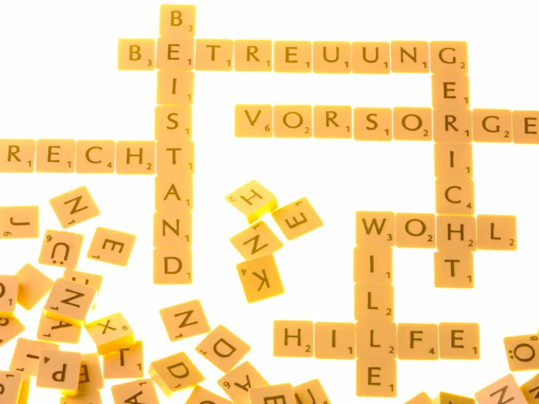 Buchstabenbausteine bilden Worte wie "Betreuung, Beistand, Vorsorge, Gericht, Wohl, Wille, Hilfe, Recht, weitere Buchstaben liegen daneben.