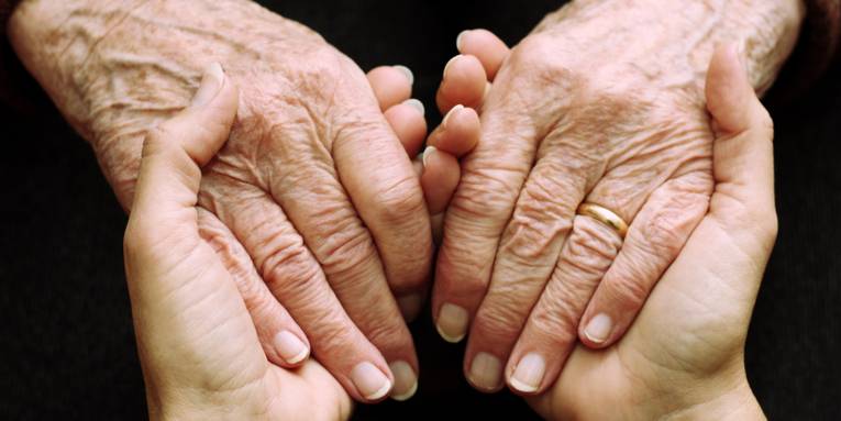 Die Hände einer jüngeren Person, die die Hände einer älteren Person halten