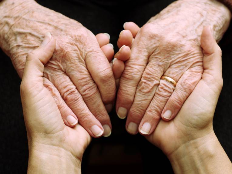 Die Hände einer jüngeren Person, die die Hände einer älteren Person halten