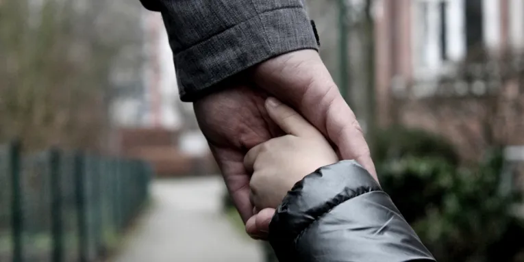 Die Hand eines Erwachsenen greift die Hand eines Kindes.