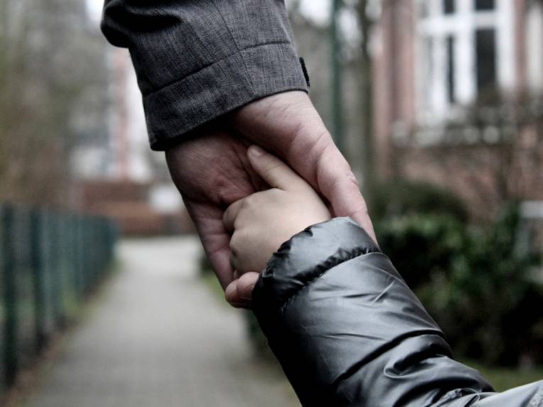 Die Hand eines Erwachsenen greift die Hand eines Kindes.