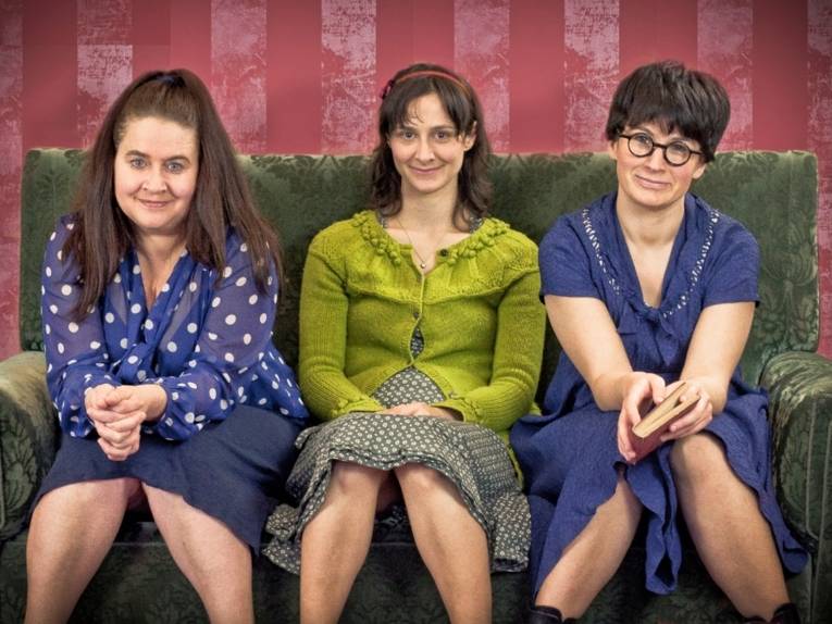 Drei Frauen sitzen auf einem Sofa.