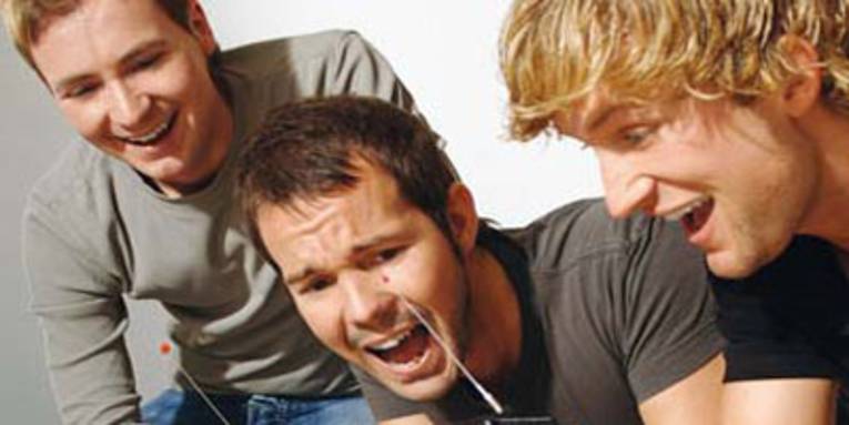 Drei Männer schauen begeistert auf Spielgeräte.