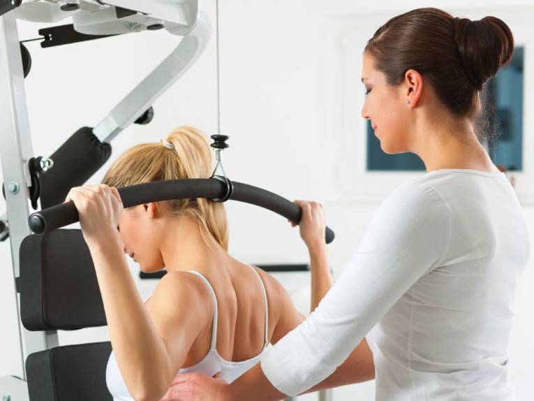 Eine Frau hilft einer anderen Frau bei einer Gymnastik-Übung.