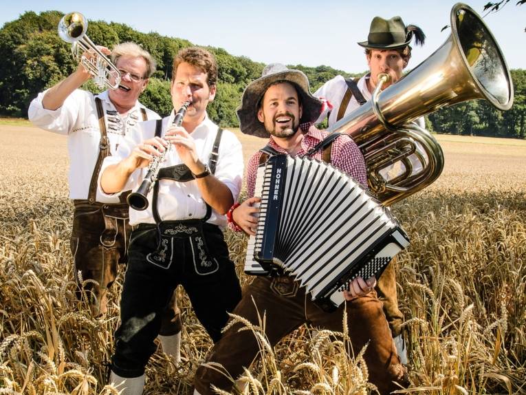 Vier Musiker stehen mit ihren Insturmenten in einem Kornfeld.
