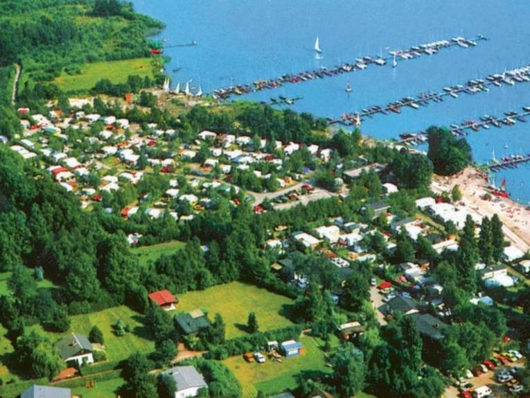Luftbildaufnahme eines Campingplatzes mit einem angrenzenden See. 