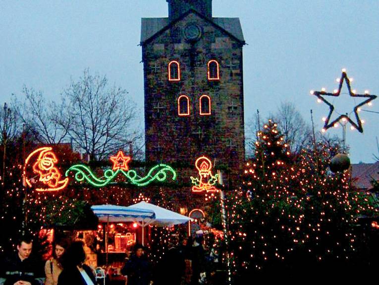 Dir Kirche mit dem idyllischen und schön beleuchteten Weihnachtsmarkt davor.