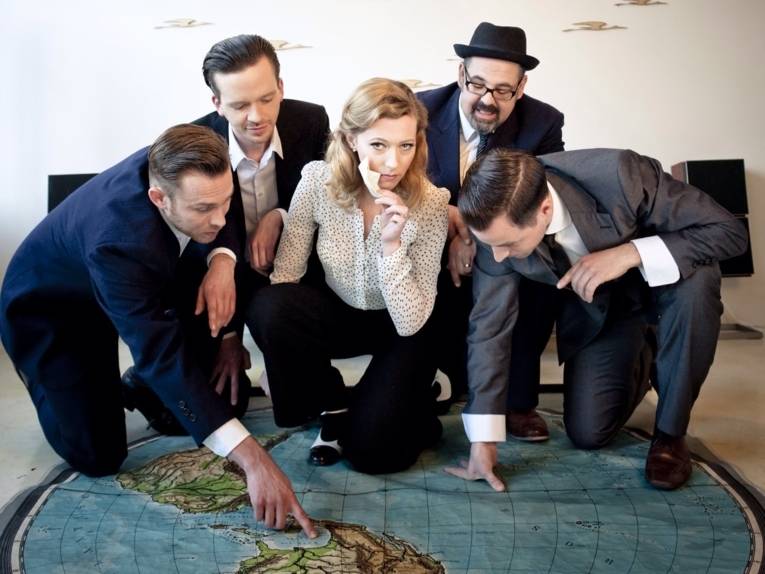 Fünf Personen suchen auf der Weltkarte nach einem bestimmten Ort.