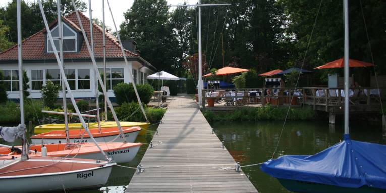 Haus an einem See mit Booten und Holzsteg