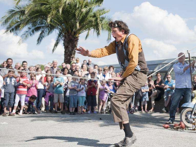 Zuschauer schauen einem Kleinkünstler zu.