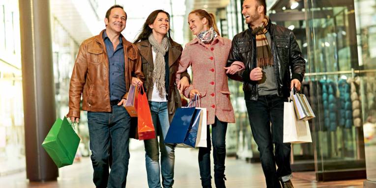 Vier Personen schlendern mit ihren Einkaufstaschen