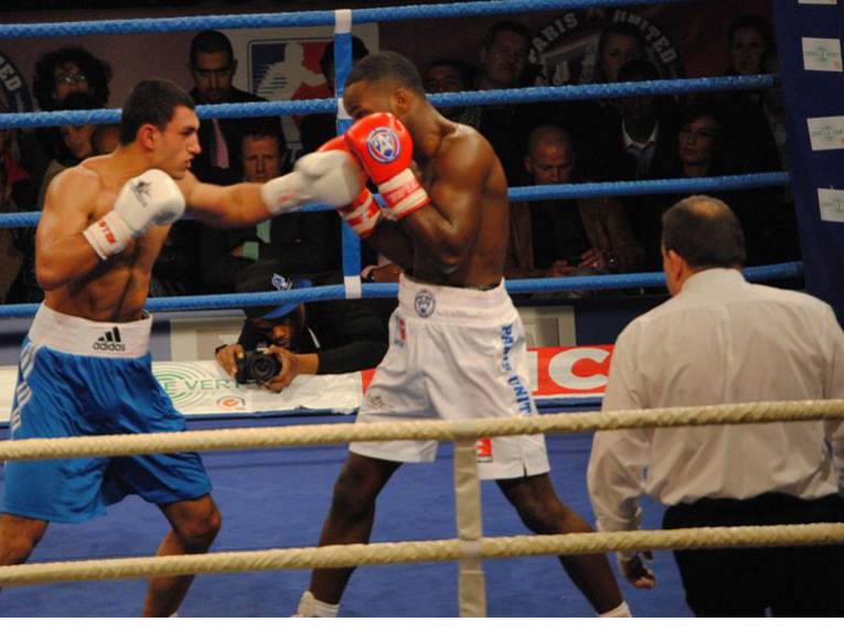 Zwei Boxer und ein Ringrichter im Ring.