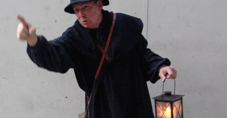 Ein Mann in einem Kostüm hält eine Lampe in der Hand.