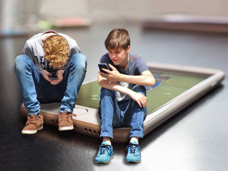 Zwei Jungs, die auf einem großen Smartphone sitzen. 