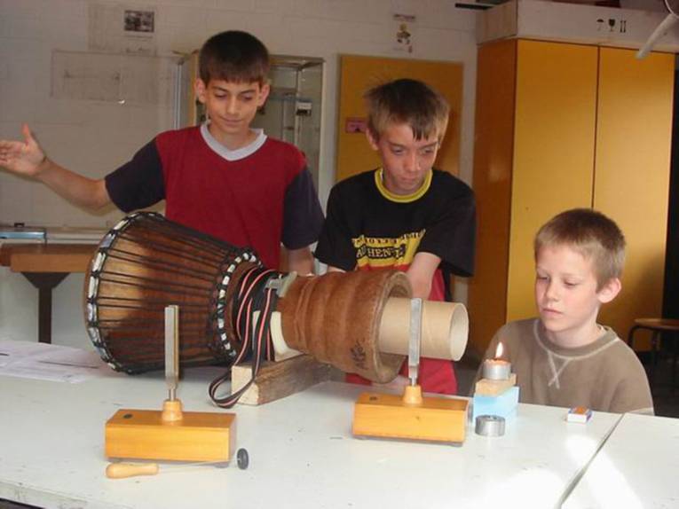 Drei Schüler experimentieren mit der Flamme einer Kerze