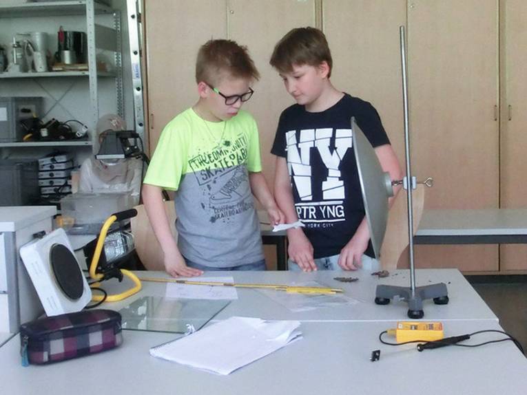 Zwei Schüler an einem Untersuchungstisch führen ein Experiment mit elektromagnetischer Strahlung durch
