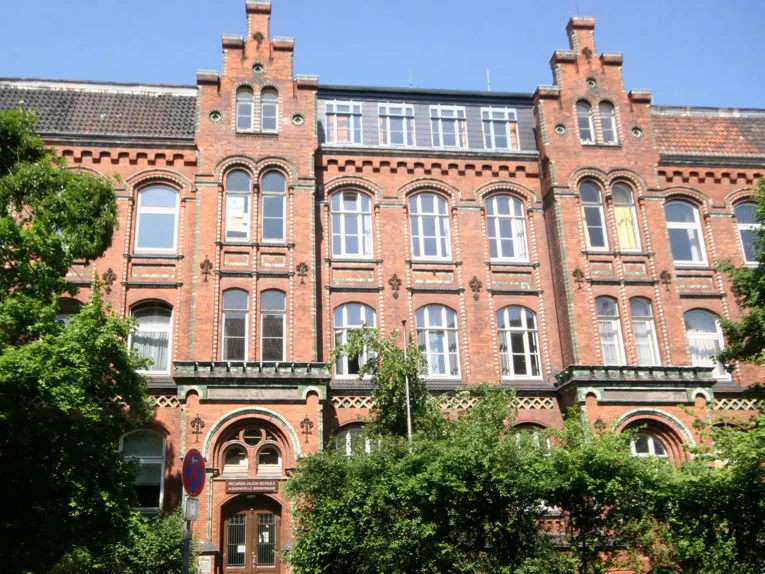 Außenaufnahme eines mehrstöckigen roten historischen Klinkergebäudes mit hohen Fenstern