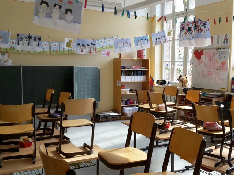 Blick in ein Klassenzimmer, das mit den Zeichnungen von Schülerinnen und Schülern geschmückt ist