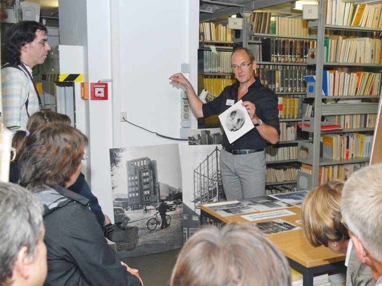 Michael Stünkel, Leiter der Stadtbibliothek an der Hildesheimer Straße, zeigt einer Gruppe von Menschen den Magazinturm und seine Schätze.