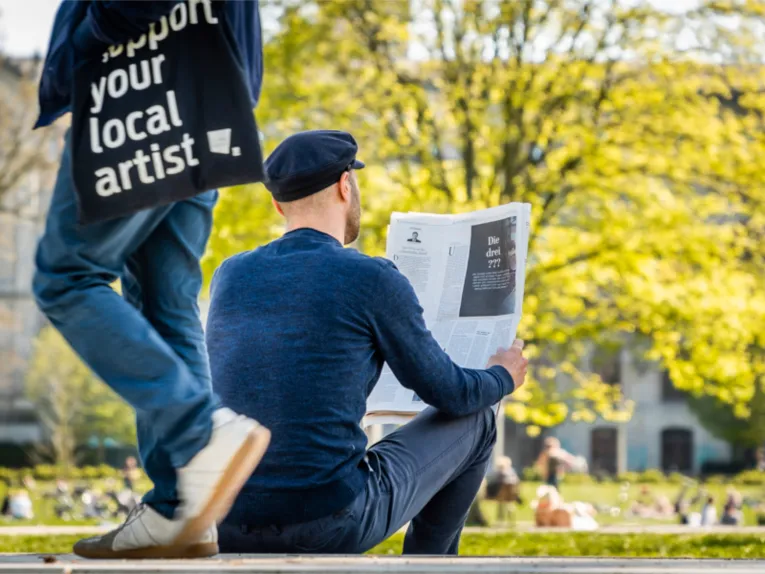 Ein Mann liest im Park eine Zeitung.