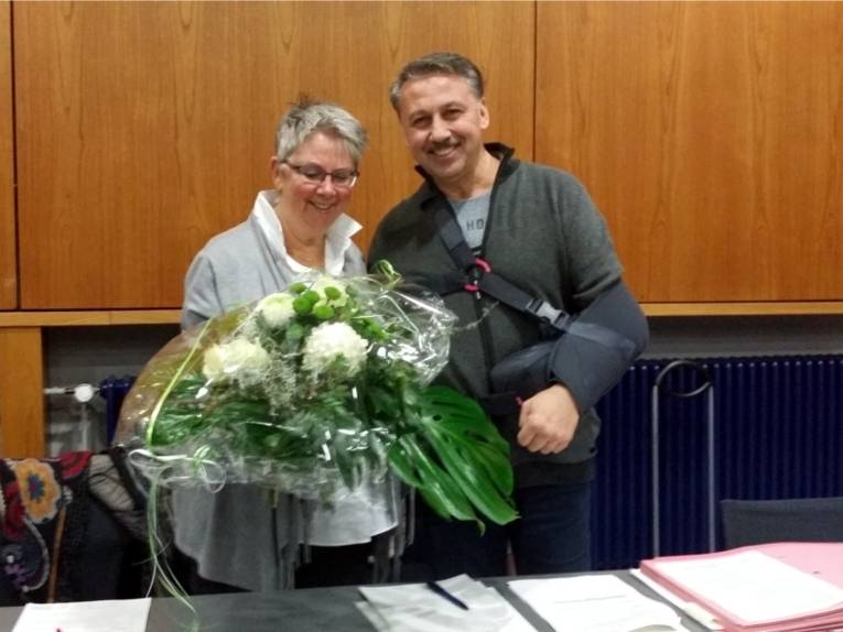Bezirksratsherr Ates überreicht der Vorsitzenden Frau Schlienkamp zum Abschied einen Blumenstrauß.
