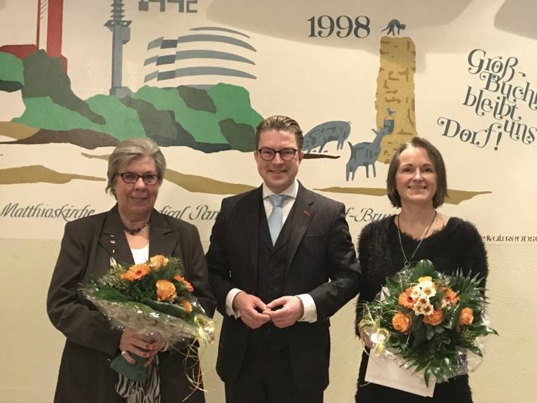 Gruppenfoto: Rechts und links des Bezirksbürgermeisters Henning Hofmann die beiden geehrten Frauen, die eine Urkunde und einen Blumenstrauß in Händen halten.
