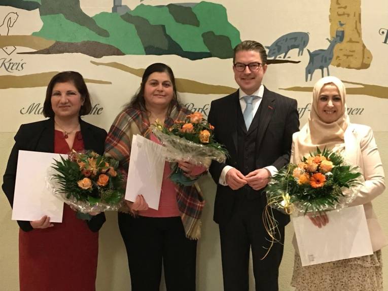 Gruppenfoto: Drei Frauen halten Urkunden und Blumensträuße in den Händen, dazwischen der Bezirksbürgermeister Henning Hofmann.