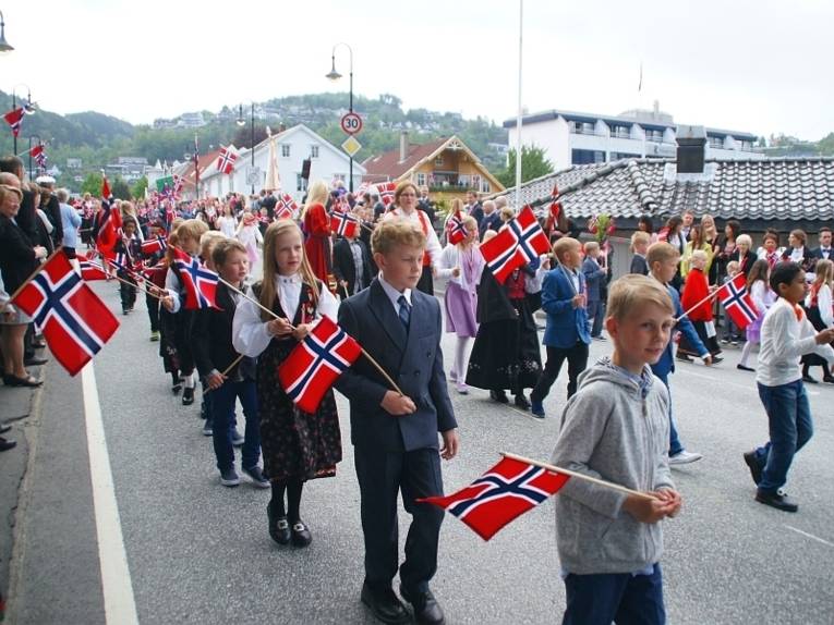 Schülerparade zum Nationalfeiertag. Die SchülerInnen sind fein angezogen und jeder trägt eine kleine norwegische Fahne.