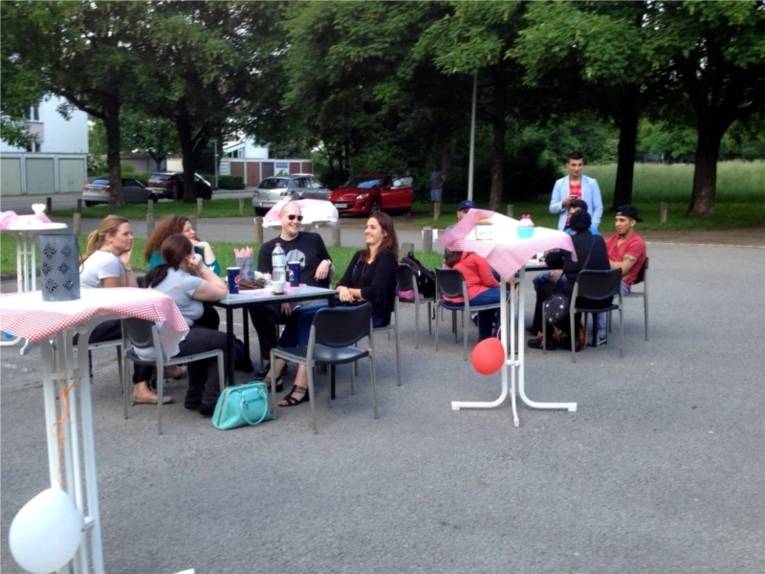 Auf dem Bild sind mehrere Stühle und Tische aufgestellt, an denen die Besucherinnen und Besucher des Grillfestes sitzen. 