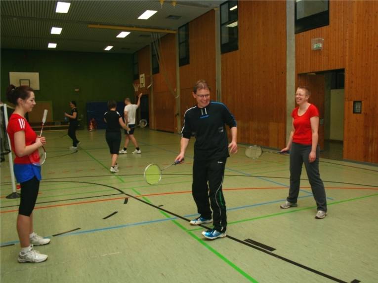 Mehrere Personen spielen zusammen Badminton und haben offenbar Spaß dabei.