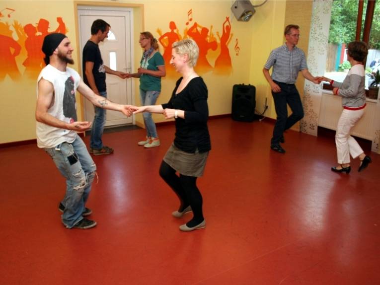 Drei Tanzpaare tanzen in einem Tanzraum einen Standardtanz.