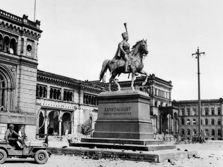 Jeep vor einem Denkmal auf einem leeren Platz im Jahr 1945.