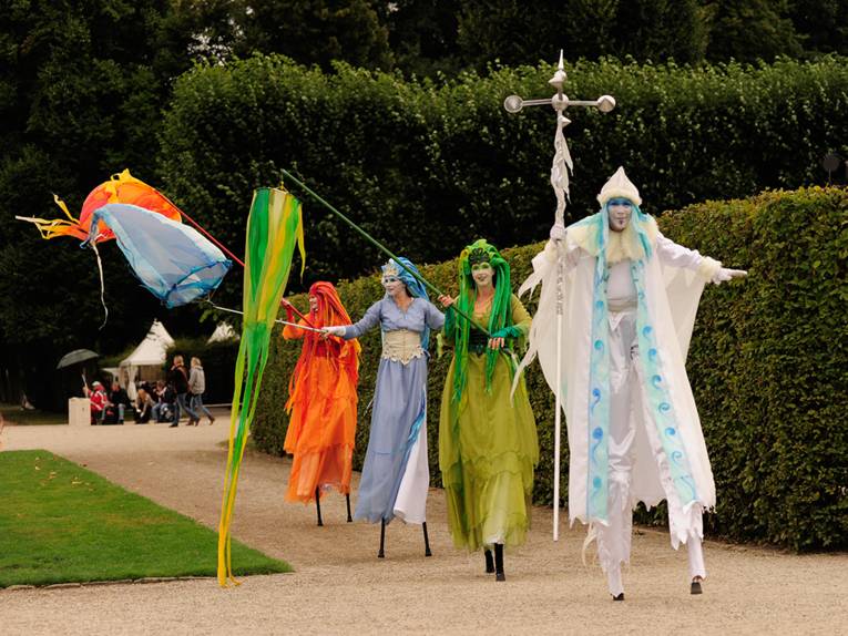 Vier bunte verkleidete Personen auf Stelzen im Großen Garten