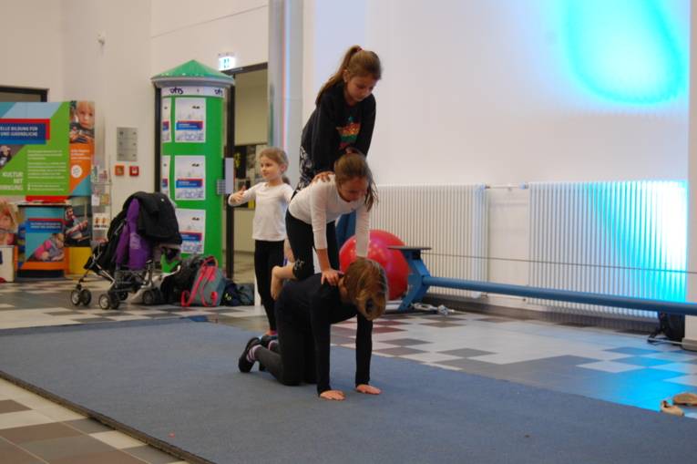 Mehrere Mädchen turnen eine akrobatische Figur.