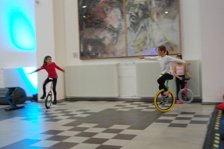 Zwei Kinder fahren auf Einrädern im Kreis herum.