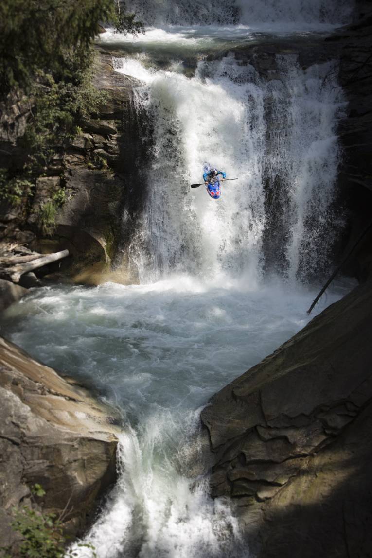 Ein Kajakfahrer befährt einen hohen Wasserfall.