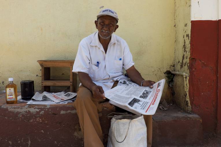 Mann mit Zeitung auf einer Mauerschwelle