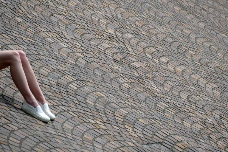 Pflaster, an der Seite Beine einer liegenden Frau