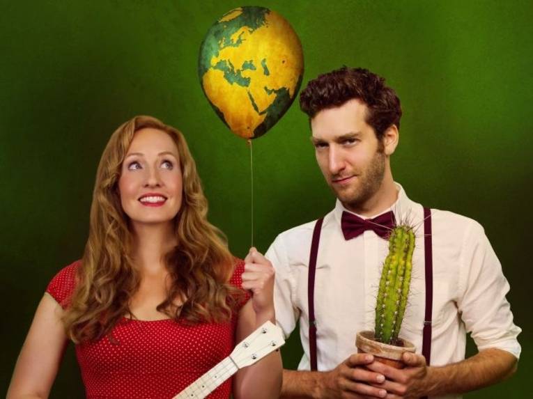 Zu sehen sind eine Frau mit einem Luftballon und ein Mann mit einem Kaktus