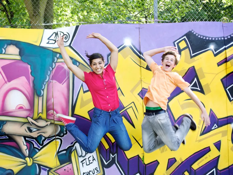 Zwei junge Leute vor einer Graffiti-Wand