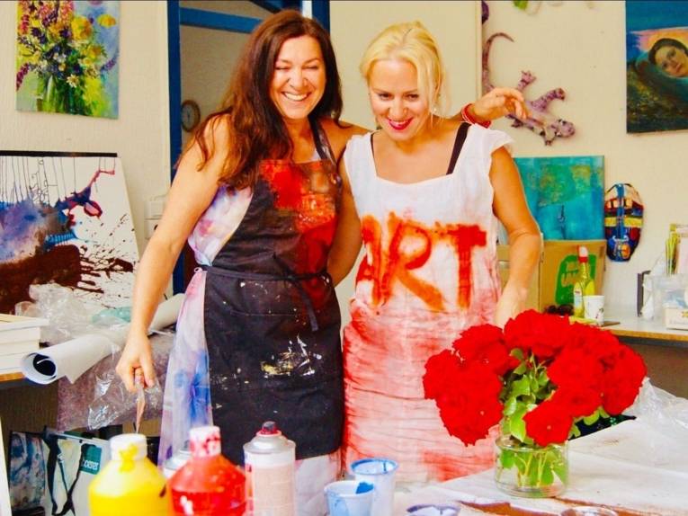 Zwei Frauen die lächelnd im Atelier malen
