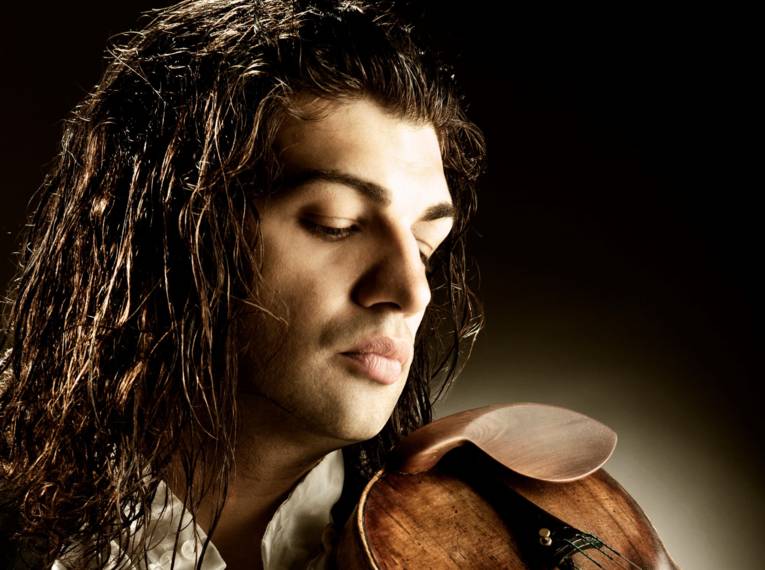 Ein Mann mit dunklen langen Locken und geschlossenen Augen hält eine Violine.
