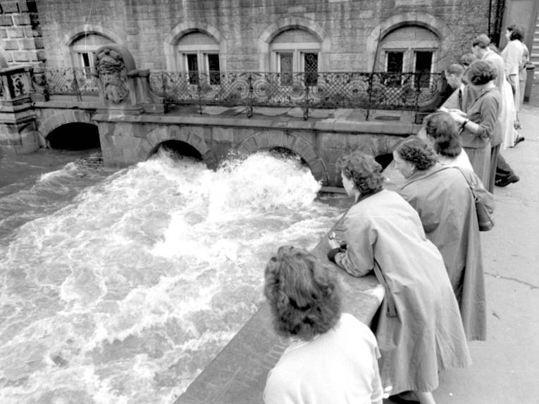 Historische Aufnahme vom Leinehochwasser am Friederikenplatz: Mehrere Frauen blicken von einer Brücke hinunter auf die Wassermassen.
